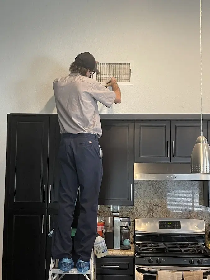 Technician inspecting an air vent during HVAC service in Eden